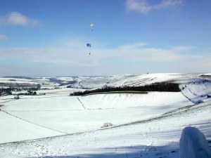 Photo of paragliders flying above snowscape