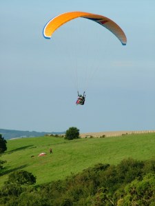Photo of a two-place paraglider flying above a hillside