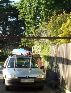 Car in yard with hang glider on roof rack