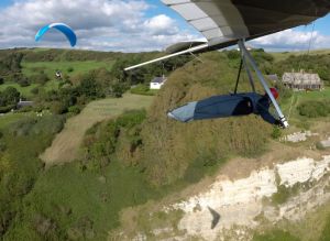 Hang glider and paraglider in flight at Ringstead, Dorset, England, in 2017