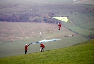 Roly Lewis-Evans waits to launch in a hang glider while Ron Smith passes in front
